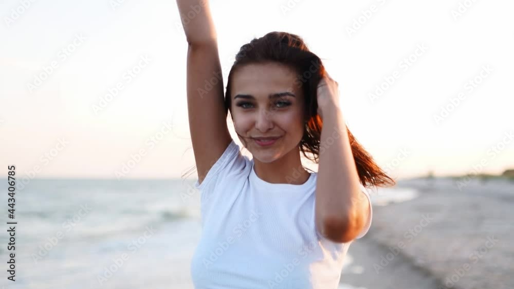 Pretty woman walking along seaside on sandy beach having fun with beer bottle. Attractive fitted girl raises hands, enjoys fredom and summer vacation near ocean shore, drinking beverage. Slow motion. Pretty woman walking along seaside on sandy beach having fun with beer bottle. Attractive fitted girl raises hands, enjoys fredom and summer vacation near ocean shore, drinking beverage. Slow motion.