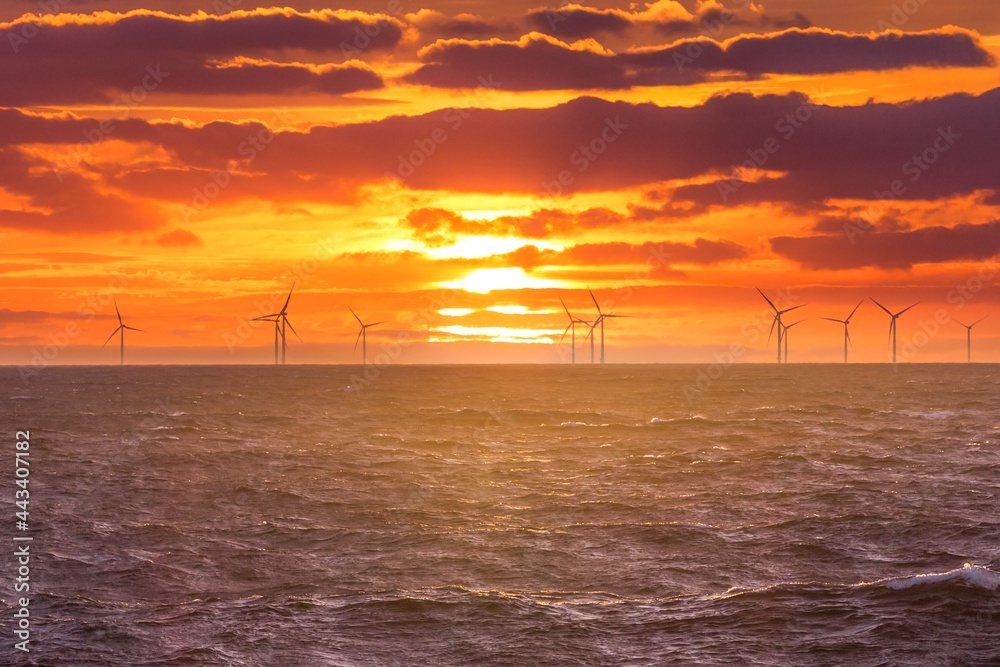 Renewable green electricity wind power generation offshore. Sunrise at decarbonization industry windmills business for regenerative energies. Clean energy renewables preventing climate change - obrazy, fototapety, plakaty 