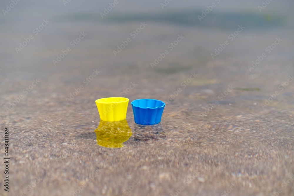 Yellow and blue plastic cupcake cup floating in the sea water