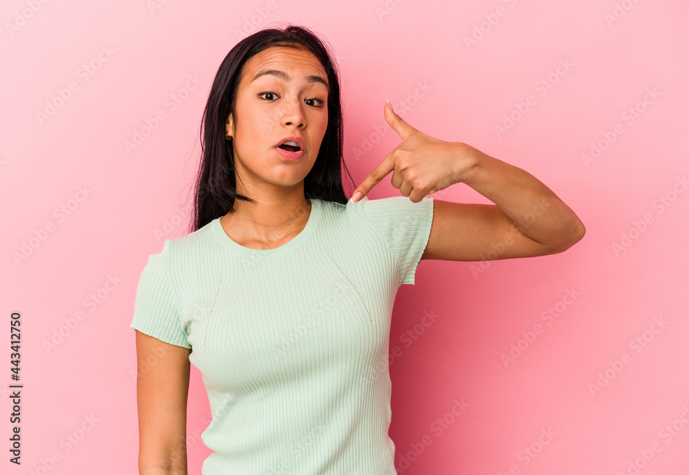 Young Venezuelan woman isolated on pink background person pointing by hand to a shirt copy space, proud and confident Young Venezuelan woman isolated on pink background person pointing by hand to a shirt copy space, proud and confident