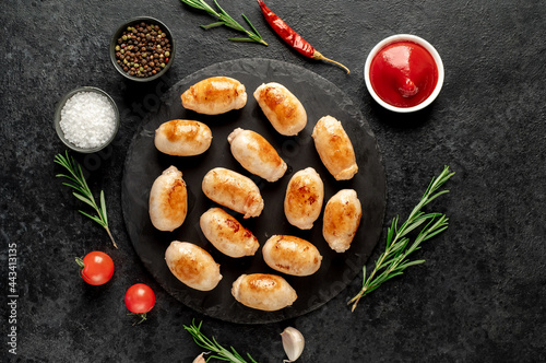 small grilled sausages on a stone background