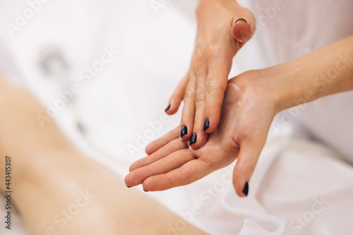 Anti-cellulite massage of hips. Woman receiving professional body  leg and foot massage and lymphatic drainage in health massage salon. Massage creme treatment.