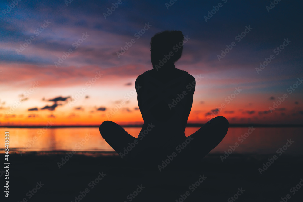 Woman meditating on beach at sunset Woman meditating on beach at sunset