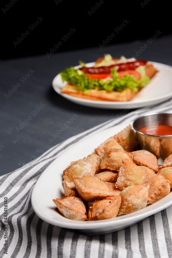 Fried dumplings stuffed with meat and served with tomato sauce on a white plate. Fried dumplings stuffed with meat and served with tomato sauce on a white plate.
