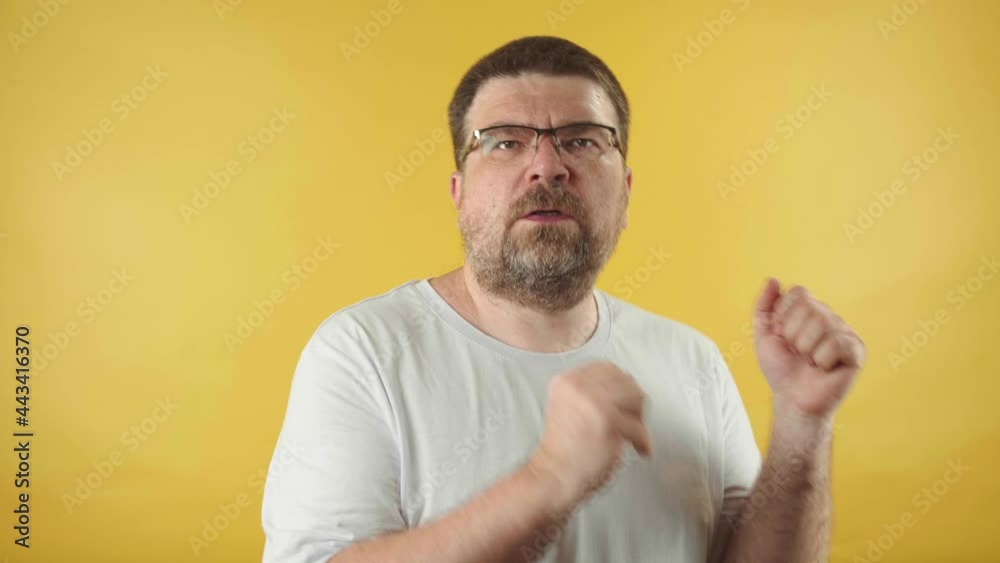 Caucasian man in glasses with a beard dances to the music isolated on a yellow background.