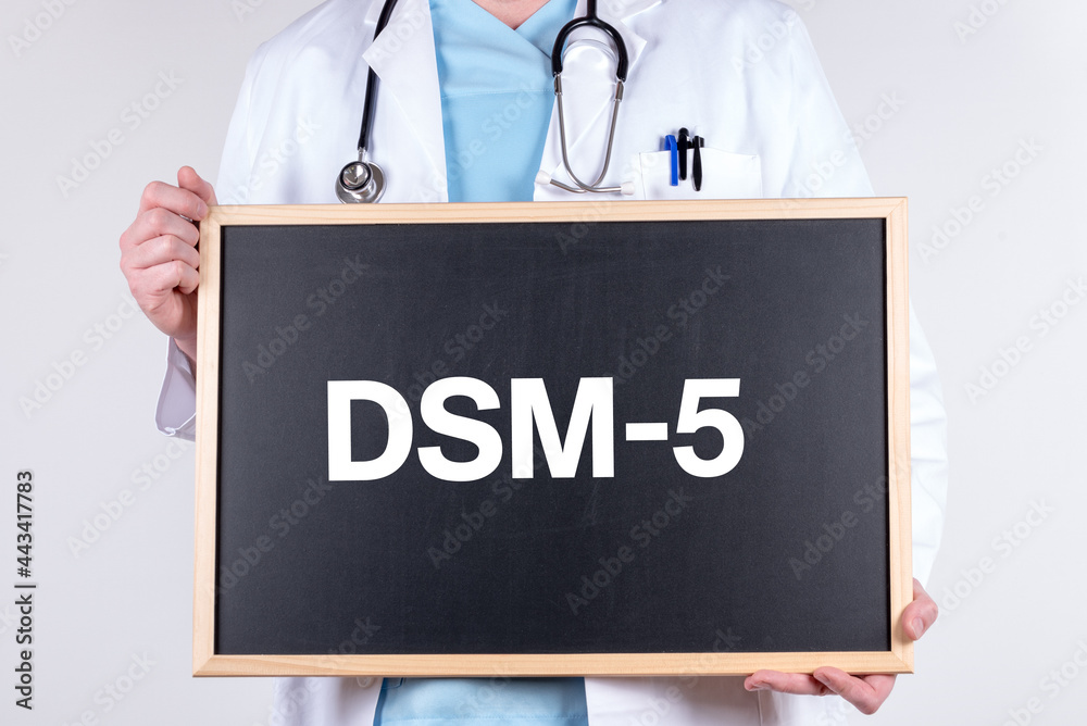 Doctor holding a blackboard with DSM-5 text Doctor holding a blackboard with DSM-5 text