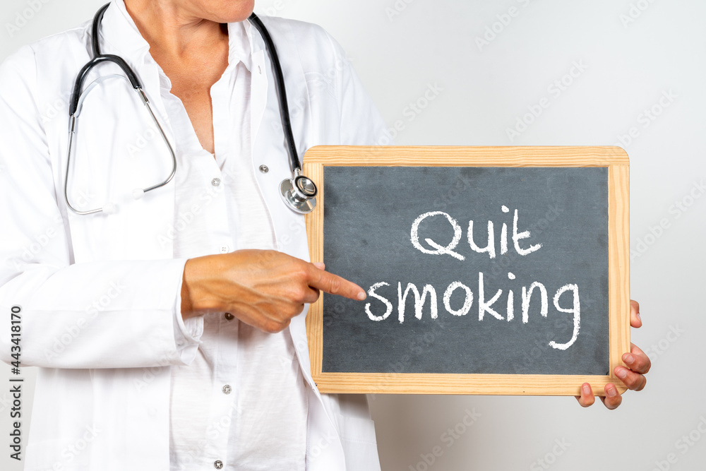 A blackboard with ''Quit smoking'' written on it in the hands of a doctor on a white background