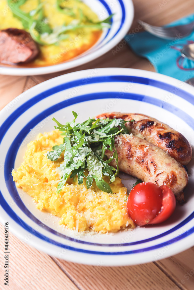 Risotto with pork sausages with cherry tomatoes and parsley on a plate. Italian cuisine concept Risotto with pork sausages with cherry tomatoes and parsley on a plate. Italian cuisine concept