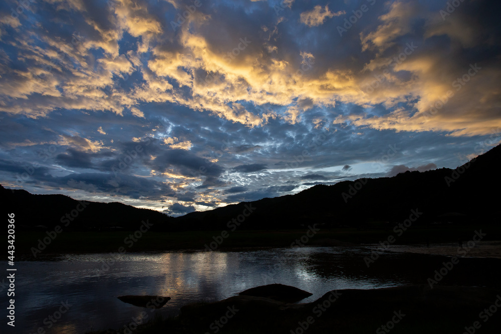 Orange cloud texture mountain silhouette landscape on blue background. River. Beautiful evening sky image for the background.