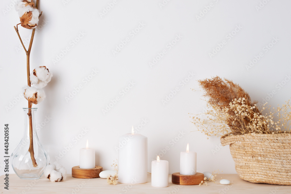 Home decoration with candles, basket and flowers over white wall. Interior design concept. Close up, copy space Home decoration with candles, basket and flowers over white wall. Interior design concept. Close up, copy space