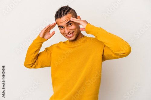 Young venezuelan man isolated on white background receiving a pleasant surprise, excited and raising hands.