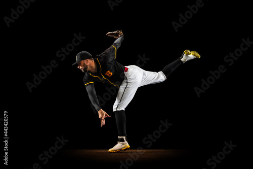 Canvas Print Professional baseball player, pitcher in sports uniform and equipment practicing isolated on a black studio background
