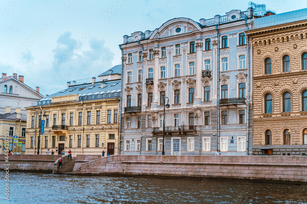Naklejka premium Beautiful historical buildings on the embankment of St. Petersburg, photographed from a boat on the river. Saint Petersburg, Russia - 28 June 2021