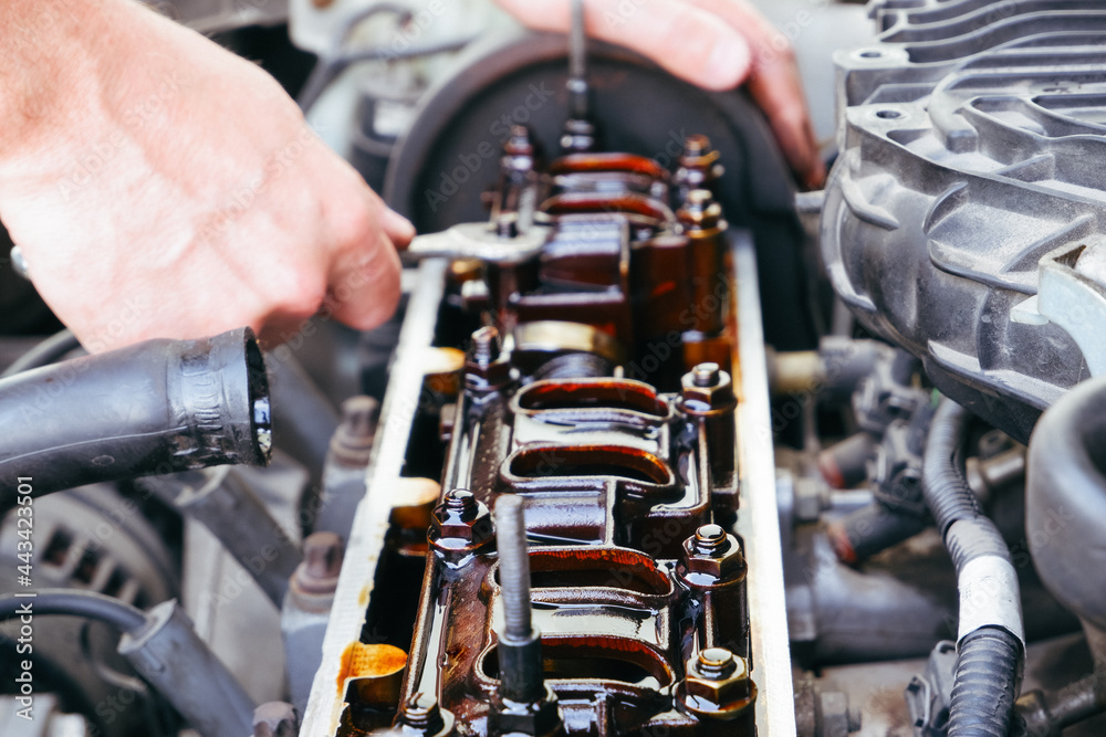 Obraz premium Car repair. The use of poor quality oil in the engine. Deposits of tar from oil on the inside of the engine. The mechanic examines the head on the internal combustion engine