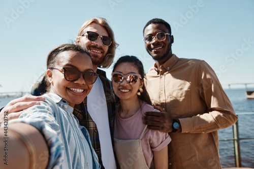 POV at diverse group of young people taking selfie outdoors in summer all wearing sunglasses