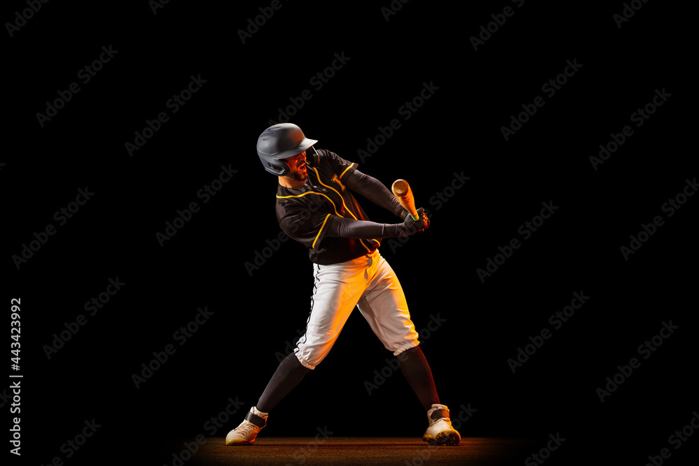 Professional baseball player, pitcher in sports uniform and equipment playing baseball isolated on black studio background in neon light. Team sport concept