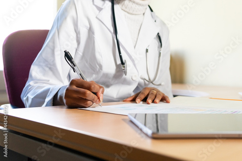 Ethnic doctor working with documents in clinic photo