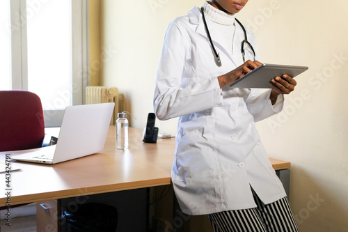 Young doctor with tablet working in office