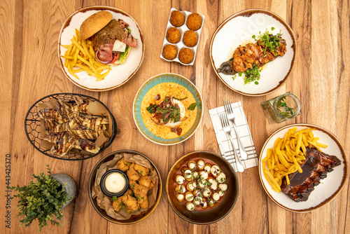 Bowl and plates of fusion food and Spanish tapas. Iberico ham croquettes, battered shark, barbecue ribs, techno-emotional patatas bravas, vegetable cream with burrata