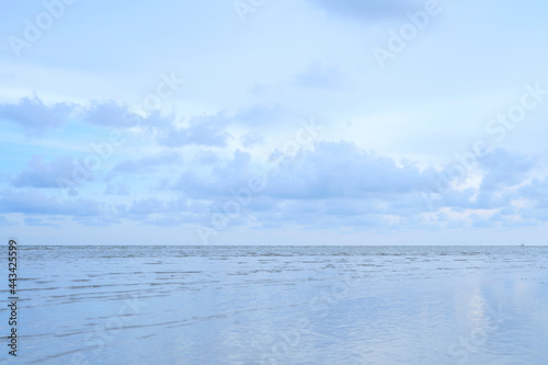 white clouds in the evening blue sky with calm sea waves The beach looks beautiful.