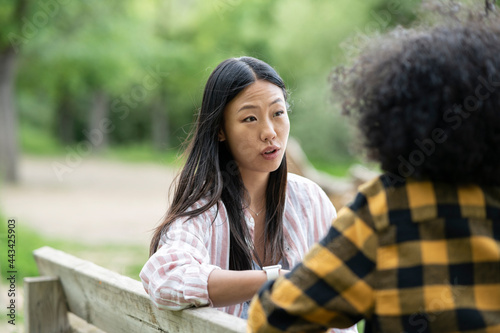 Lesbian couple of multiethnic women holding hands near lake