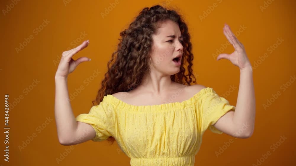 Young curly woman showing bla-bla gesture isolated on yellow background Young curly woman showing bla-bla gesture isolated on yellow background