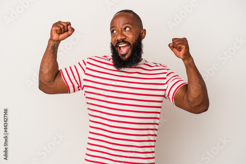 African american man with beard isolated on pink background raising fist after a victory, winner concept.