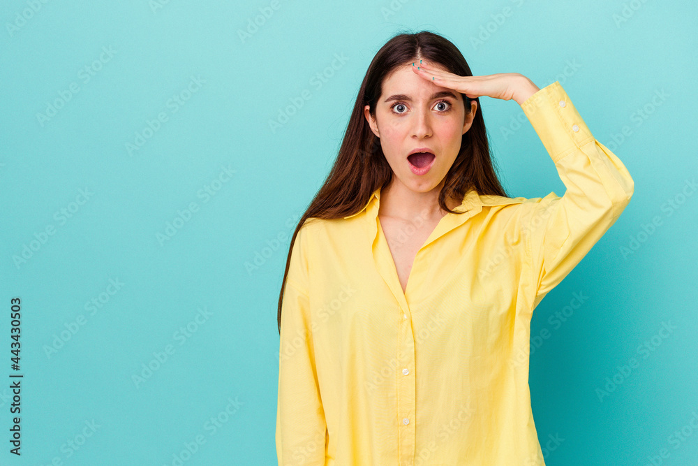 Young caucasian woman isolated on blue background shouts loud, keeps eyes opened and hands tense. Young caucasian woman isolated on blue background shouts loud, keeps eyes opened and hands tense.