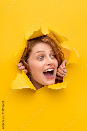 Amazed woman peeking out from hole in paper © kegfire