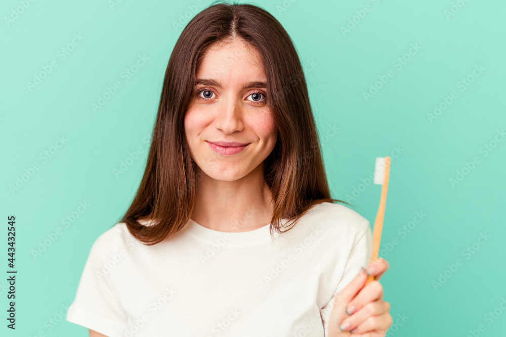 Young caucasian woman holding a toothbrush isolated on blue background Young caucasian woman holding a toothbrush isolated on blue background