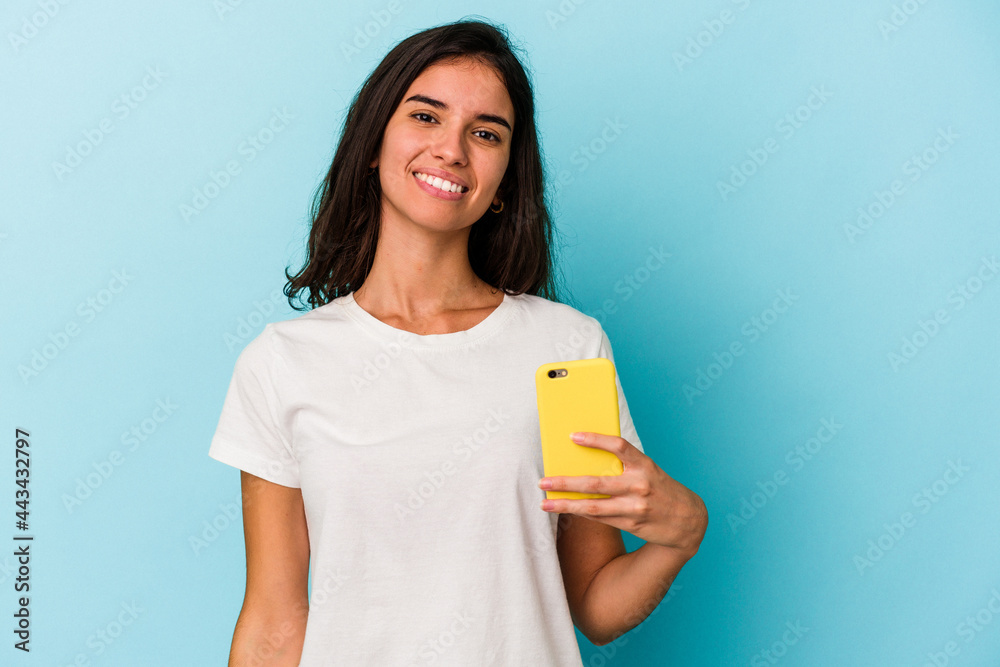 Young caucasian woman holding a mobile phone isolated on blue background happy, smiling and cheerful. Young caucasian woman holding a mobile phone isolated on blue background happy, smiling and cheerful.