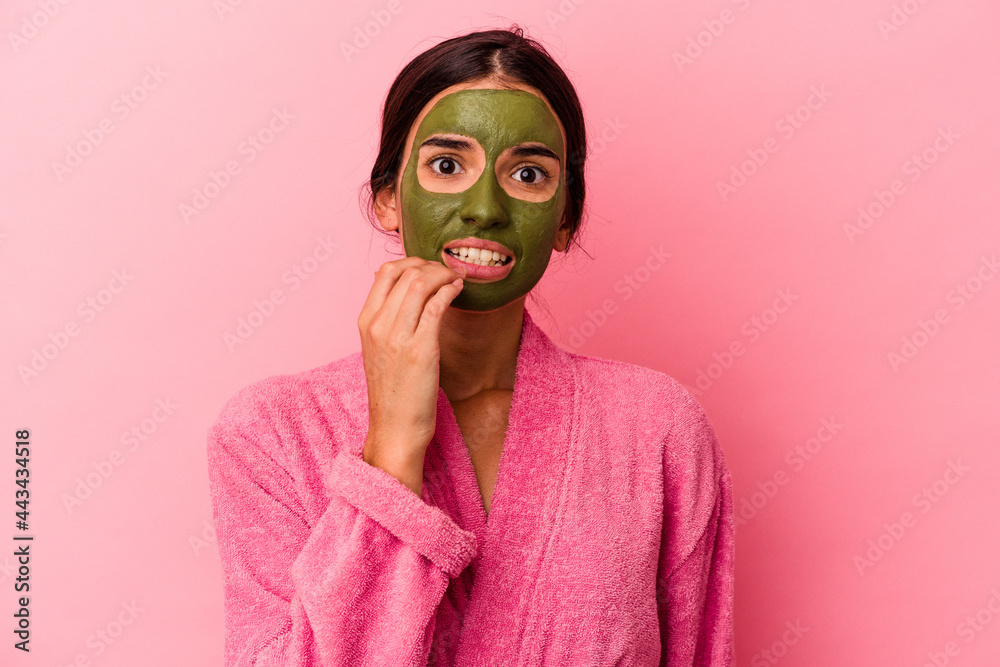 Young caucasian woman wearing a bathrobe and facial mask isolated on pink background biting fingernails, nervous and very anxious. Young caucasian woman wearing a bathrobe and facial mask isolated on pink background biting fingernails, nervous and very anxious.