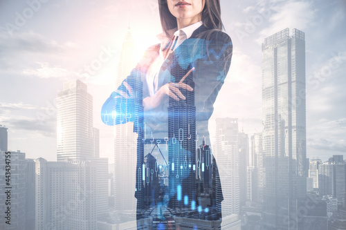 Pretty young european businesswoman with folded arms standing on abstract bright city background with forex chart and mockup place. Finance, trade and success concept. Double exposure. © Who is Danny