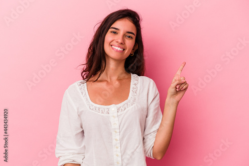 Young caucasian woman isolated on pink background showing number one with finger. © Asier