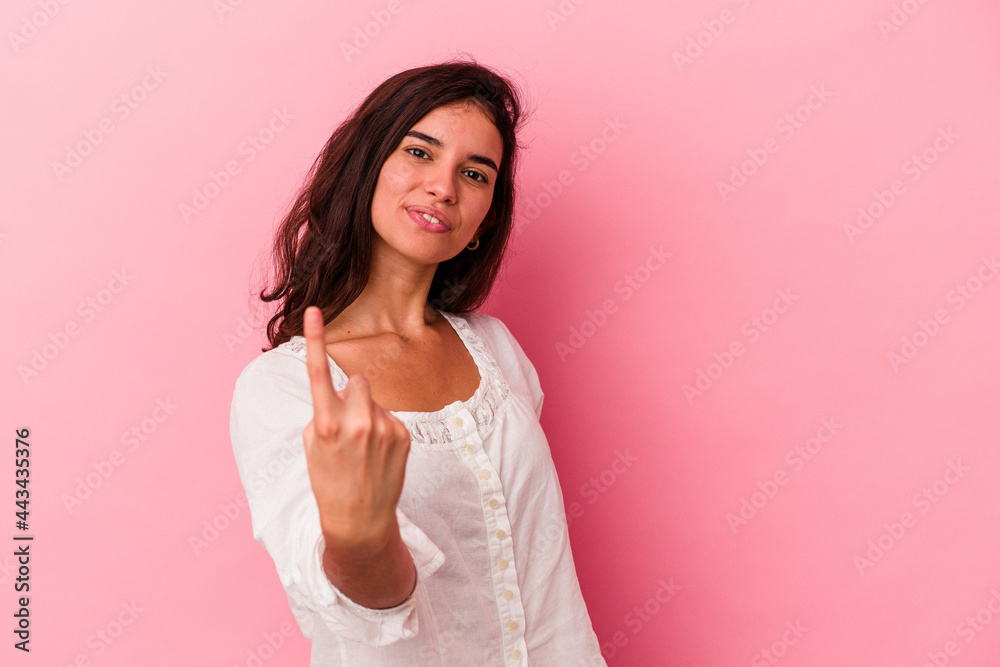 Young caucasian woman isolated on pink background pointing with finger at you as if inviting come closer. Young caucasian woman isolated on pink background pointing with finger at you as if inviting come closer.