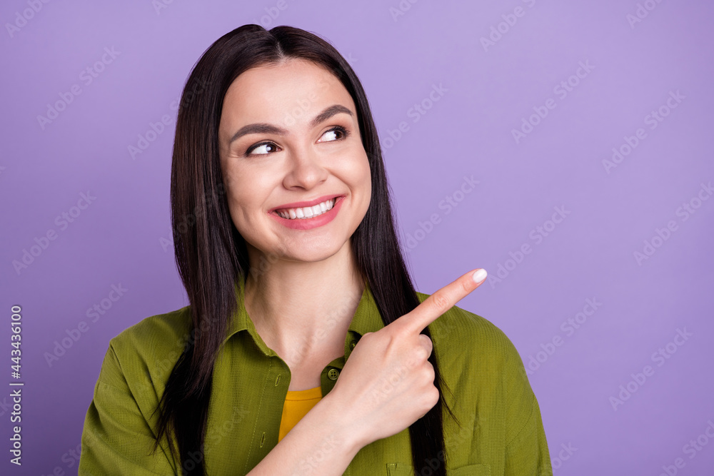 Photo of dreamy shiny young lady dressed green clothes smiling looking pointing finger empty space isolated purple color background Photo of dreamy shiny young lady dressed green clothes smiling looking pointing finger empty space isolated purple color background