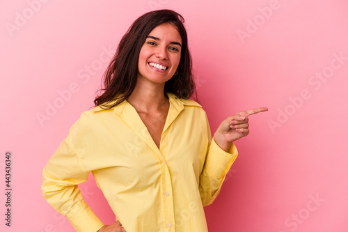 Young caucasian woman isolated on pink background smiling cheerfully pointing with forefinger away.