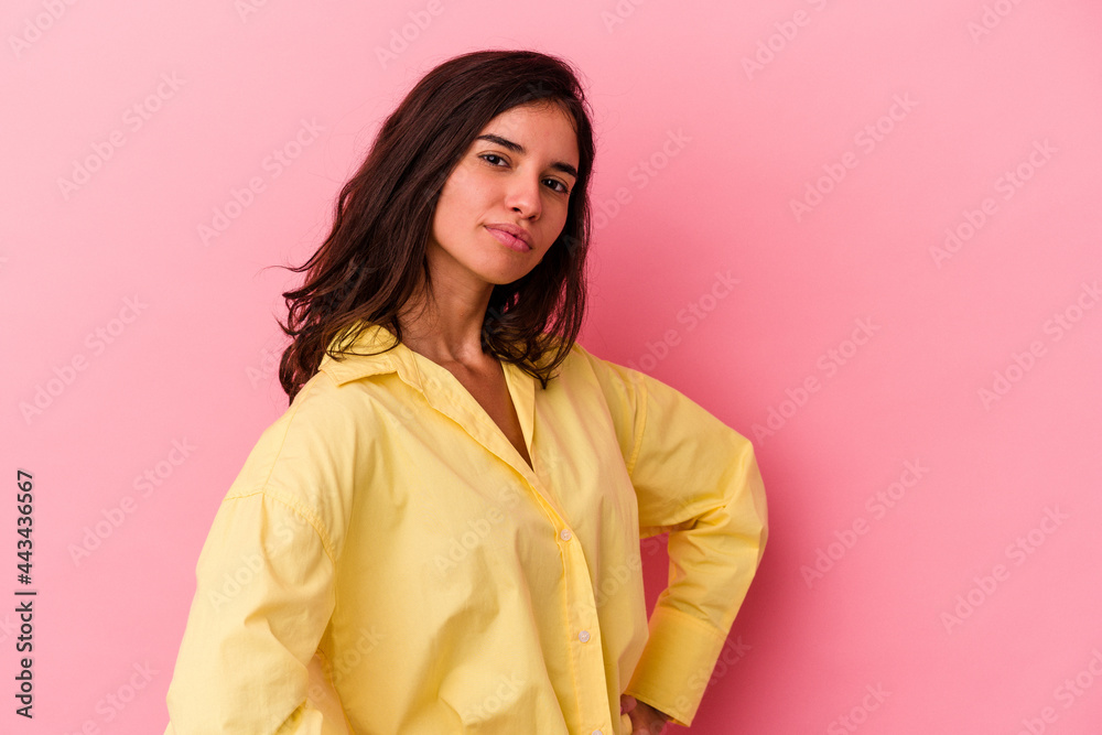 Young caucasian woman isolated on pink background frowning face in displeasure, keeps arms folded.