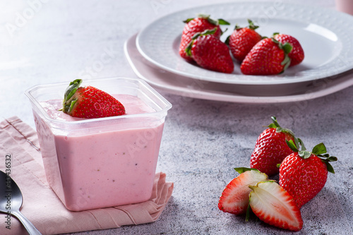 .Delicious strawberry mousse in a plastic cup for delivery with fresh strawberries.