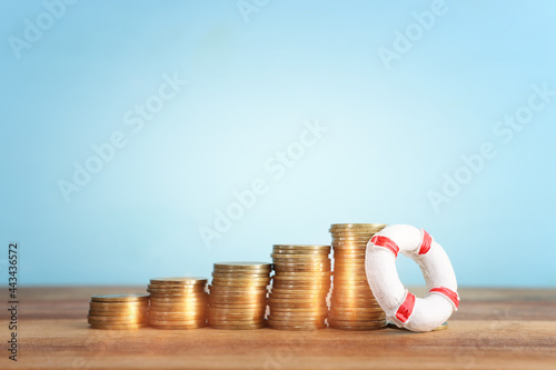 concept image of stacked coins and life bouy over wooden background. banking, funds and assistance idea photo