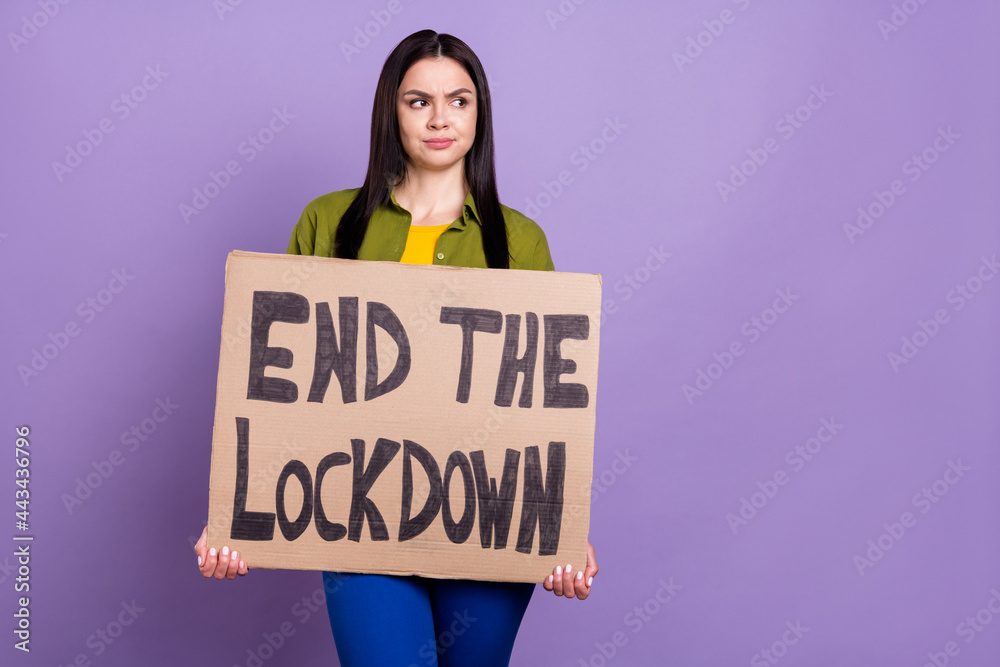 Photo of depressed sad lady dressed green clothes holding end lockdown placard looking empty space isolated purple color background Photo of depressed sad lady dressed green clothes holding end lockdown placard looking empty space isolated purple color background