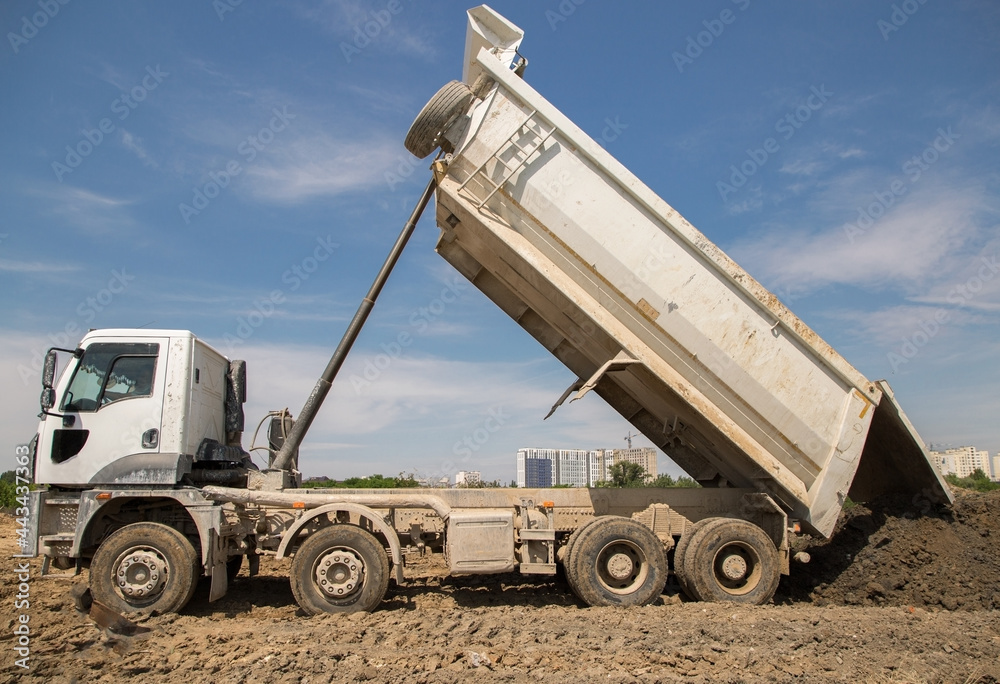 dump truck at work at a construction site. The process of transporting unloading soil on a construction machine. Excavation. tipper with raised body