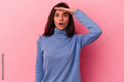 Young caucasian woman isolated on pink background looking far away keeping hand on forehead. © Asier