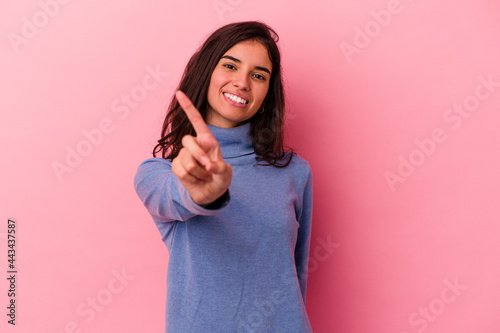 Young caucasian woman isolated on pink background showing number one with finger.
