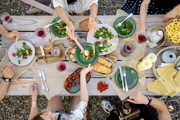 Group of people dining outdoors, view from above on the beautifully decorated wooden table with healthy food and drinks