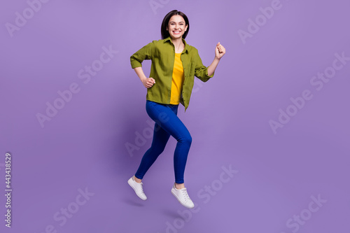 Full length profile side photo of young girl happy positive smile jump up go run hurry isolated over violet color background © deagreez