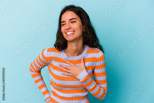 Young caucasian woman isolated on blue background laughing keeping hands on heart, concept of happiness.