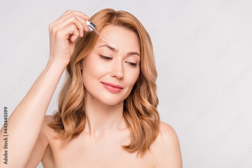 Portrait of attractive dreamy woman applying hyaluronic bio serum on forehead isolated over grey pastel color background Portrait of attractive dreamy woman applying hyaluronic bio serum on forehead isolated over grey pastel color background