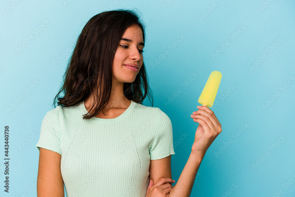 Young caucasian woman holding an ice cream isolated on blue background Young caucasian woman holding an ice cream isolated on blue background