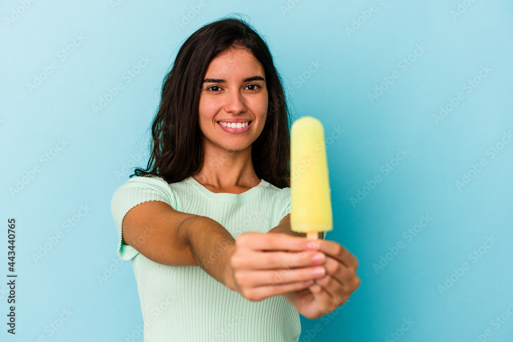 Young caucasian woman holding an ice cream isolated on blue background Young caucasian woman holding an ice cream isolated on blue background
